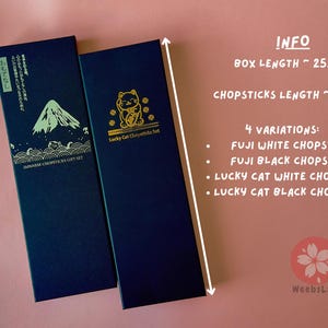 Op de afbeelding: Twee zwarte cadeaudozen met gouden opschriften. De doos aan de linkerkant heeft een Japans berglandschap en de tekst "Japanese Chopsticks Gift Set". De doos aan de rechterkant heeft een gouden gelukkat-ontwerp en de tekst "Lucky Cat Chopsticks Set".