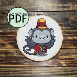 May include: Cross stitch pattern PDF for a cute cartoon monkey wearing a red and yellow circus outfit. The monkey is sitting with its legs crossed and has a big smile on its face.