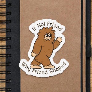 Pu&ograve; includere: Un adesivo con un'illustrazione di un cartone animato di una creatura marrone simile a Bigfoot con il testo "If Not Friend Why Friend Shaped".