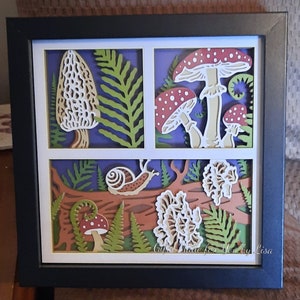 May include: A papercraft art piece featuring a variety of mushrooms and a snail. The mushrooms are in shades of red, white, and brown, and the snail is a light brown color. The background is a dark blue color, and the piece is framed in a black frame. The text "Crafts Made for You by Lisa" is visible in the bottom right corner.