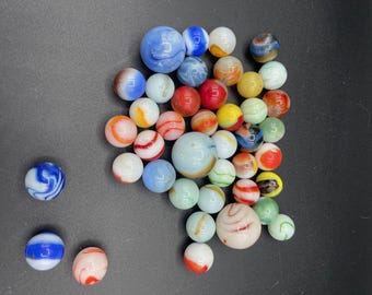 May include: A collection of colorful glass marbles with various patterns and swirls. The marbles are mostly white, blue, red, and green.
