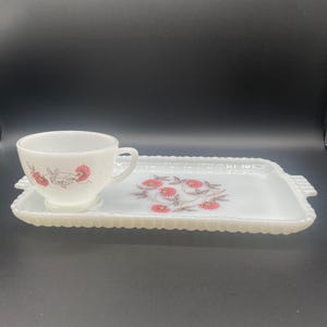 May include: White milk glass serving tray with a floral design in pink and brown. The tray has a scalloped edge and a small cup with a matching design.