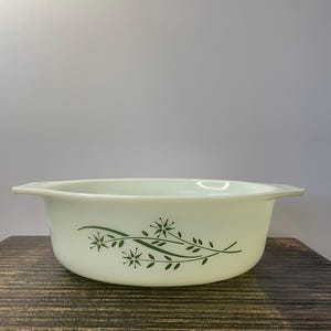 以下が含まれることがあります： 緑色の花柄が施された白い楕円形のベーキングディッシュ。デザインは、スタイリッシュな葉と花を特徴としています。