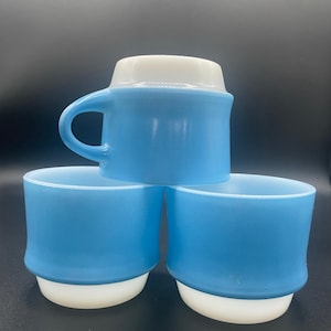 Puede incluir: Conjunto de tres tazas de cerámica azul y blanca. Las tazas tienen un borde y una base blancos, y el cuerpo es de color azul claro.