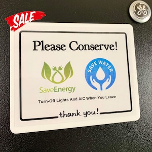 May include: White sign with black border and text that reads "Please Conserve!" with two logos. The first logo is green and says "SaveEnergy" with a stylized image of a power cord. The second logo is blue and says "Save Water" with a stylized image of two hands holding a water drop. The text below the logos reads "Turn-Off Lights And A/C When You Leave" and "thank you!"