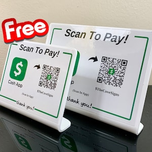 Puede incluir: Dos letreros de mostrador blancos con bordes verdes y texto negro que dicen "Scan To Pay!" con un código QR y el texto "$TheCoveSigns". El letrero de la izquierda también tiene un logotipo verde de Cash App y el texto "Cash App" y "(Scan In App)". Ambos letreros tienen el texto "thank you!" en la parte inferior.