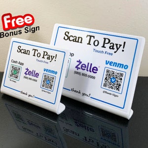 Puede incluir: Dos letreros de mostrador blancos con texto negro que dice "Scan To Pay!" y "Touch Free". Los letreros tienen códigos QR para Cash App, Zelle y Venmo.