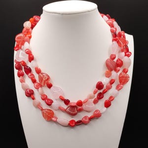 May include: Multi-strand necklace made of red, pink and white heart-shaped beads.