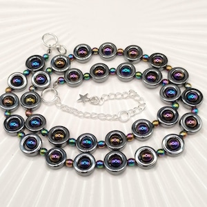 以下が含まれることがあります： 虹色の黒ヘマタイトビーズでできた2連ネックレス。ビーズは丸型で、中央に小さな円があります。ネックレスには、星形のチャームが付いたシルバーチェーンが付いています。