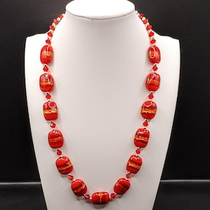 May include: A red and gold glass bead necklace with silver accents. The beads are rectangular and have a striped pattern.
