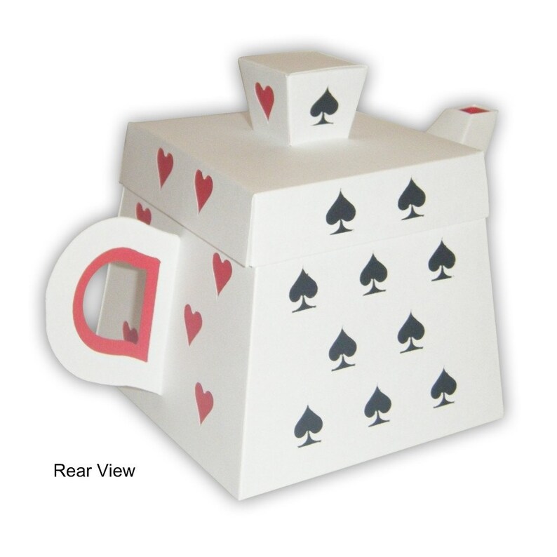 May include: White cardboard teapot shaped box with a red handle and red hearts and black spades printed on the sides. The box is closed and the lid is on top. The text "Rear View" is printed below the box.
