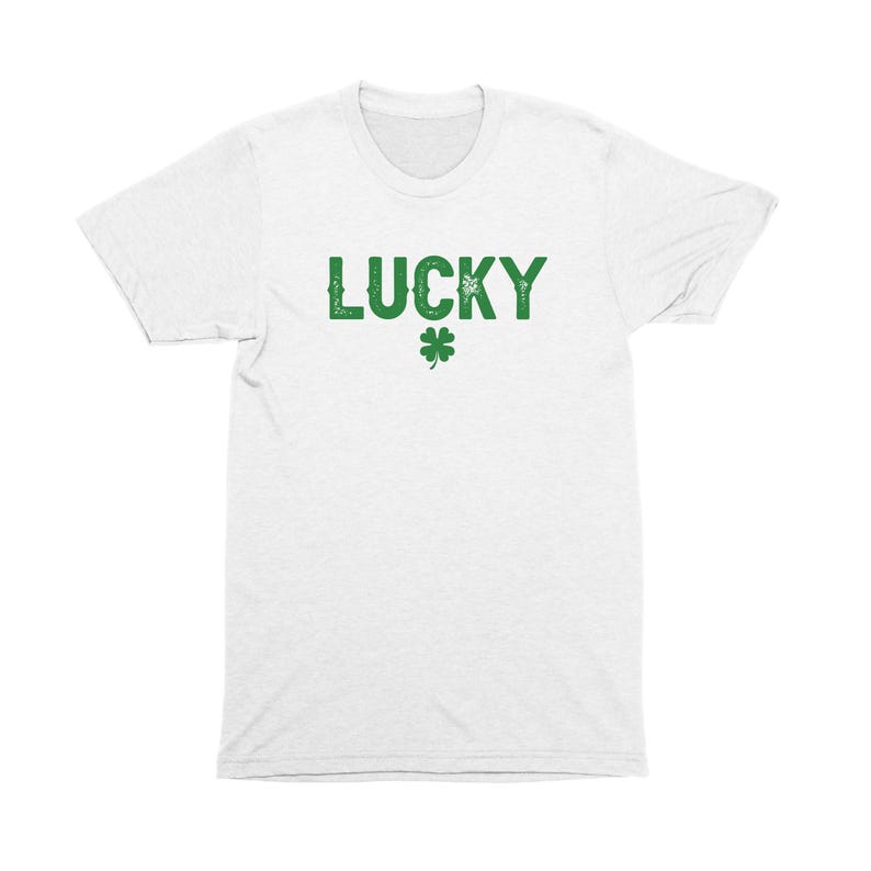 Op de afbeelding: Wit T-shirt met het woord "LUCKY" in groene letters en een groen klavertje vier.