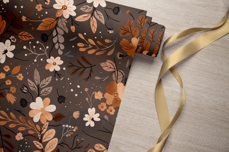 May include: A roll of brown wrapping paper with a floral pattern featuring white and orange flowers and leaves. A gold ribbon is lying on a wooden surface.