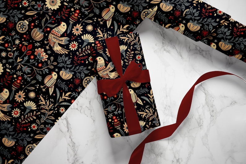Puede incluir: Un regalo envuelto en papel de regalo estampado en blanco y negro con una cinta roja. El papel presenta un patr&oacute;n repetitivo de p&aacute;jaros, flores y hojas.