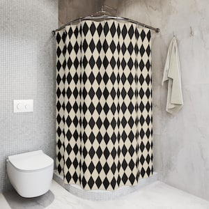 May include: A black and white diamond patterned shower curtain with gold accents. The curtain is hung in a bathroom with a white toilet and tiled walls.