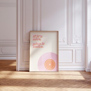 May include: A rectangular framed wall art print featuring a cream background with the text "If it's nice, play it twice." in pink and orange lettering, positioned above a stylized graphic of a pink and orange vinyl record at the bottom.
