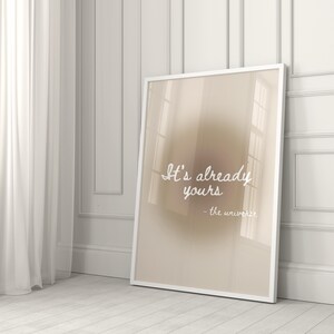 Könnte beinhalten: Ein beiger Poster mit einem weißen Rahmen. Der Poster hat einen Verlaufshintergrund und den Text "It's already yours - the universe" in weißer kursivschrift.