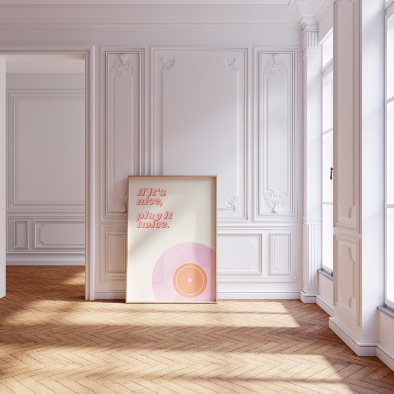 May include: A rectangular framed wall art print featuring a cream background with the text "If it's nice, play it twice." in pink and orange lettering, positioned above a stylized graphic of a pink and orange vinyl record at the bottom.