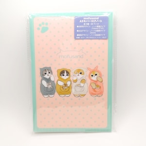 以下が含まれることがあります： 透明なプラスチック製のカバーが付いた薄い青色のA5ノートカバー。カバーは、白い水玉模様のピンク色の背景に、フード付きのパジャマを着た4匹の猫のイラストが描かれています。カバーの上部と下部には黒い文字で「mofusand」と印刷されています。