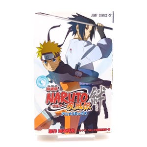 以下が含まれることがあります： 表紙に2人のアニメキャラクターが描かれた漫画。タイトル「NARUTO」が大きく表示されています。一人はとげのある金髪、もう一人は黒髪で、剣を持っています。本は白で、日本語のテキストとジャンプコミックスのロゴが入っています。