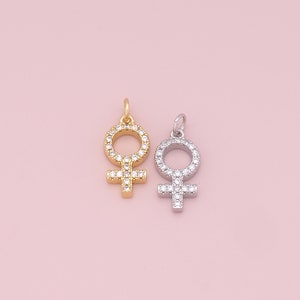 May include: Two silver and gold charms in the shape of the female symbol, both with clear crystal accents.