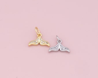 May include: Two mermaid tail charms, one gold and one silver, with clear crystal accents.