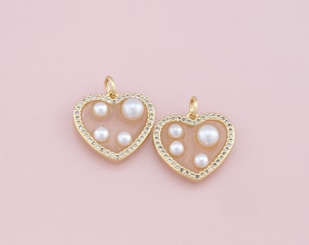 May include: Two gold heart-shaped charms with a clear resin center and white pearl accents. The charms have a gold border with small clear rhinestones.