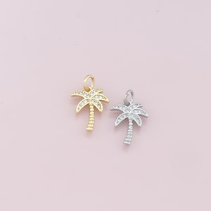 May include: Two palm tree charms, one gold and one silver, with clear crystal accents.