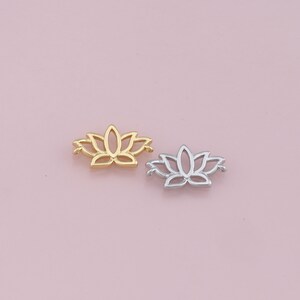 Puede incluir: Dos abalorios de metal con forma de flor de loto, uno dorado y otro plateado, con un delicado diseño calado.