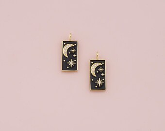 May include: Two gold-toned charms with black enamel and clear rhinestone accents. Each charm features a crescent moon and a star design.
