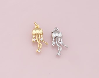 Puede incluir: Dos colgantes de amuleto, uno dorado y otro plateado, con forma de medusa con detalles de cristal transparente.