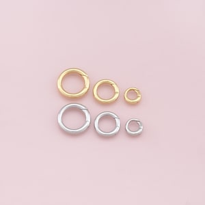 Puede incluir: Seis anillos de salto de diferentes tamaños, cuatro plateados y dos dorados. Los anillos están dispuestos en una fila, con el anillo más grande a la izquierda y el más pequeño a la derecha.