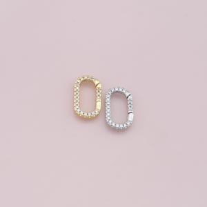 May include: Two oval-shaped jewellery clasps with a pave diamond setting. One clasp is gold and the other is silver.