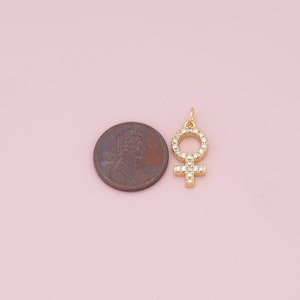 May include: Gold-toned charm featuring a female symbol with clear cubic zirconia stones.