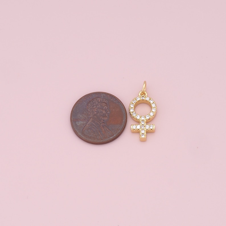 May include: Gold-toned charm featuring a female symbol with clear cubic zirconia stones.