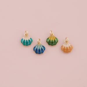 May include: Four gold-colored shell charms with enamel paint in different colors. The shells are blue, green, orange, and white.