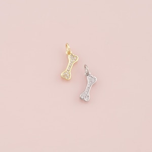 May include: Two dog bone charms, one gold and one silver, with clear crystals.