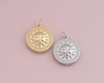 May include: Two sun pendant charms, one gold and one silver, with a face and rays. The charms are on a pink background.