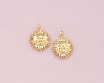 May include: Two gold sun charm pendants with a face on each. The sun has a detailed design with rays.