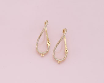 May include: A pair of gold-tone earrings with a teardrop shape and a clear crystal design.