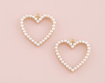 May include: Two gold heart-shaped charms with a pearl border. The charms have a loop at the top for attaching to jewelry.