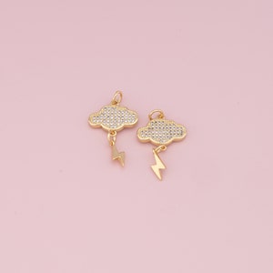 May include: Two gold-tone charms in the shape of a cloud with a lightning bolt dangling from the bottom. The clouds are covered in clear sparkling rhinestones.