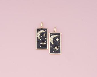 May include: Two gold-toned charms with black enamel and clear crystal accents. Each charm features a crescent moon and stars on a black background.