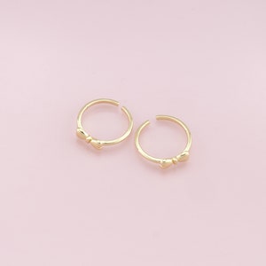 May include: Two gold-toned rings with a bow design. The rings are simple and delicate.