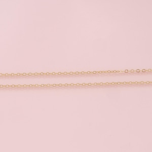 K&ouml;nnte beinhalten: Zwei goldene Ketten auf rosa Hintergrund. Die Ketten bestehen aus kleinen, miteinander verbundenen Kreisen.