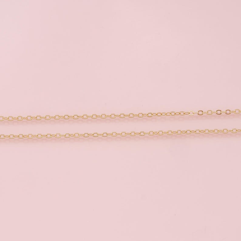 K&ouml;nnte beinhalten: Zwei goldene Ketten auf rosa Hintergrund. Die Ketten bestehen aus kleinen, miteinander verbundenen Kreisen.