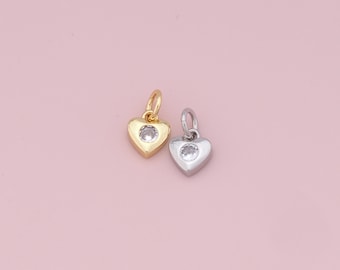 Puede incluir: Dos abalorios en forma de corazón con un strass transparente en el centro. Un abalorio es dorado y el otro es plateado.