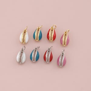 May include: Eight teardrop-shaped charms in various colors: white, teal, red, and pink. Each charm has a gold or silver-colored bail and a decorative center. The charms are displayed on a light pink background.
