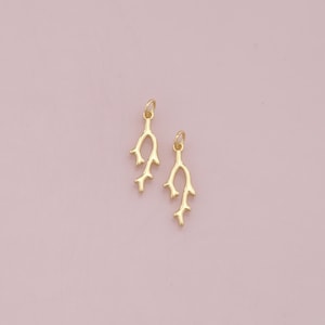 May include: Two gold-colored metal charms shaped like branches with multiple offshoots. The charms are perfect for jewelry making or adding a touch of nature to crafts.