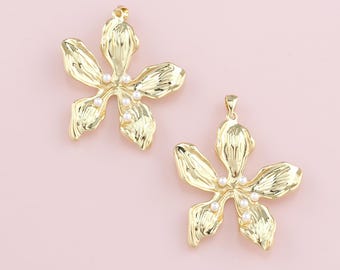 May include: Two gold flower charms with five petals each. The flowers have a textured surface and are adorned with small white pearls.
